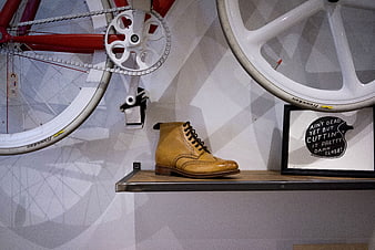Tan leather boot on shelf with red bicycle and quote art