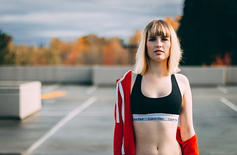 Blonde woman in sportswear standing in parking lot