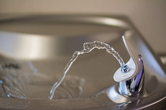 Close-up of a stainless steel drinking fountain with water flowing