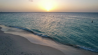 Serene Sunset Over Calm Ocean Waves and Sandy Beach
