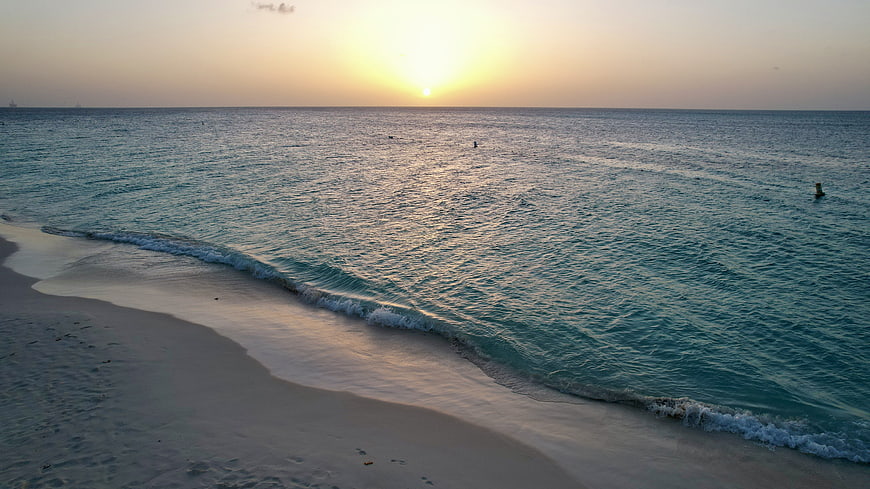 Serene Sunset Over Calm Ocean Waves and Sandy Beach
