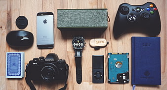 Flat lay of tech gadgets, camera, and notebook on wood