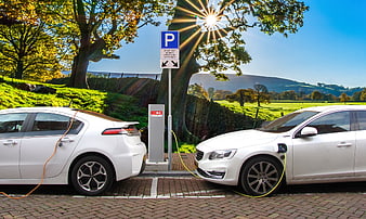 Two white electric cars charging at a rural station
