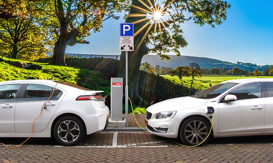 Two white electric cars charging at a rural station