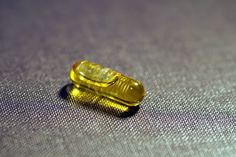 Yellow Fish Oil Capsule on Textured Gray Surface