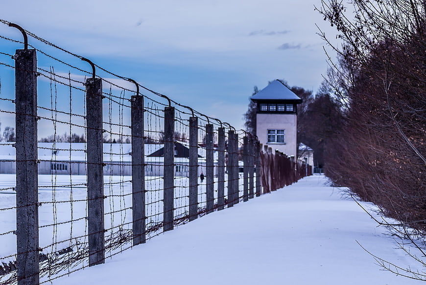 Barbed wire fence and watchtower at Dachau concentration camp in winter