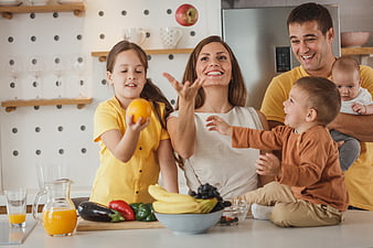 Happy family playing with fruit in modern kitchen