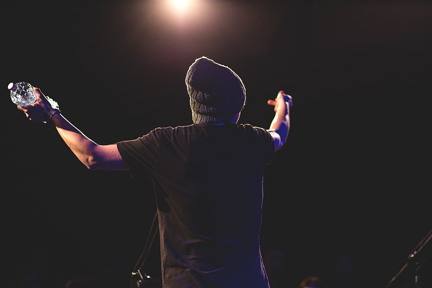 Back view of male performer on stage with raised arms