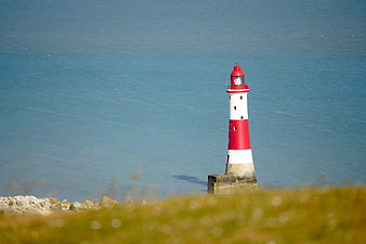 Red and white lighthouse on calm blue sea coast
