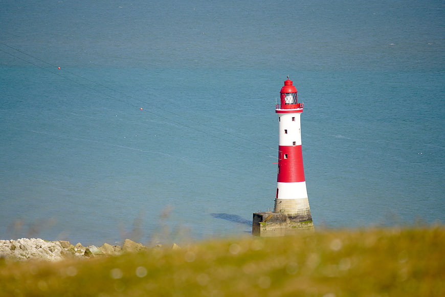 Red and white lighthouse on calm blue sea coast