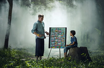 Teacher teaching alphabet to child in misty forest