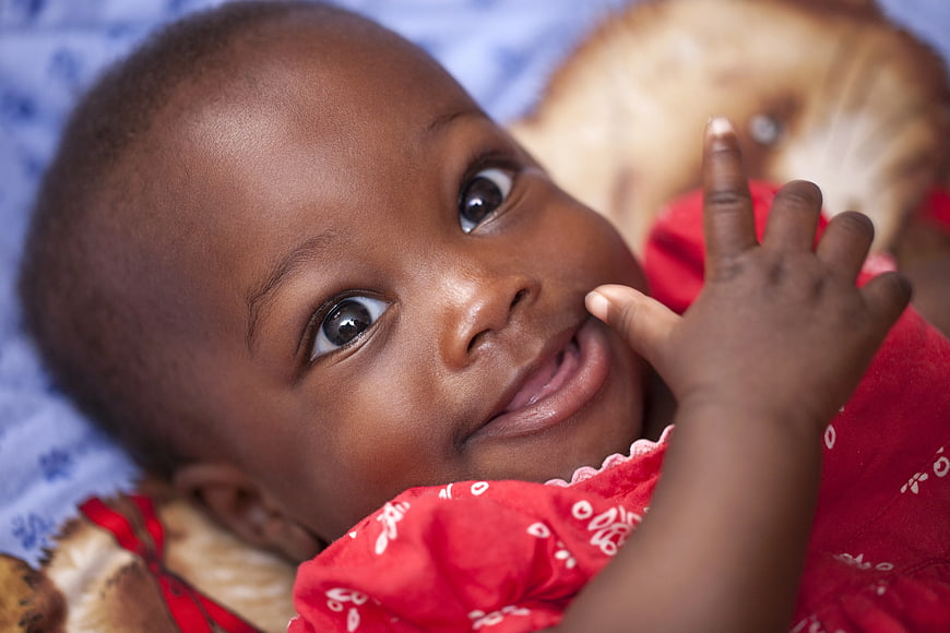 Close-up of smiling baby in red dress with stuffed animal