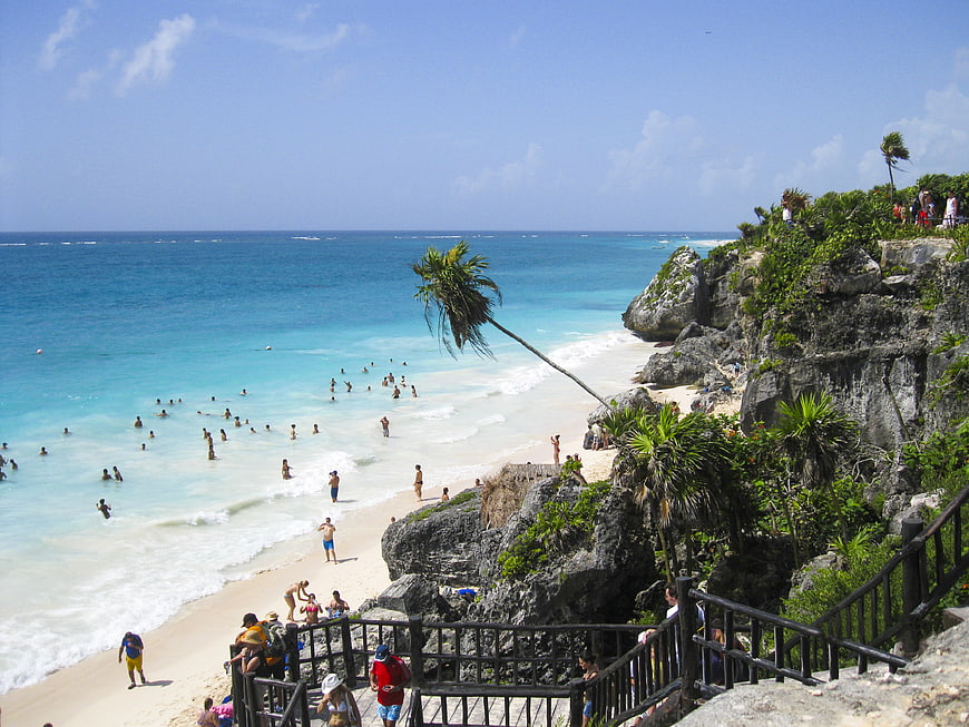 Aerial View of Turquoise Beach with Cliffside Stairs and Palm Trees