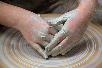 Close-up of hands shaping wet clay on a spinning pottery wheel