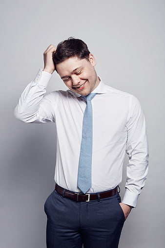 Happy businessman scratching head in white shirt and tie