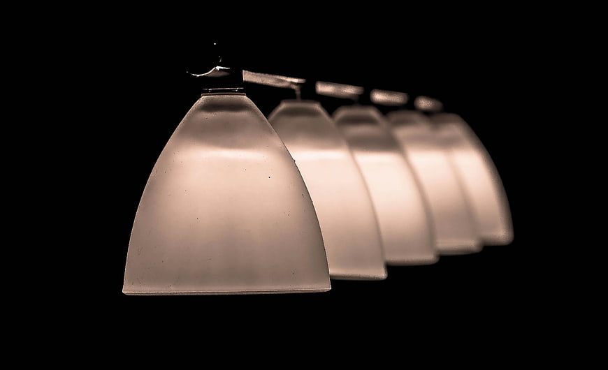 Row of frosted glass pendant lights on black background