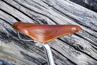 Brown leather bicycle saddle on weathered driftwood background