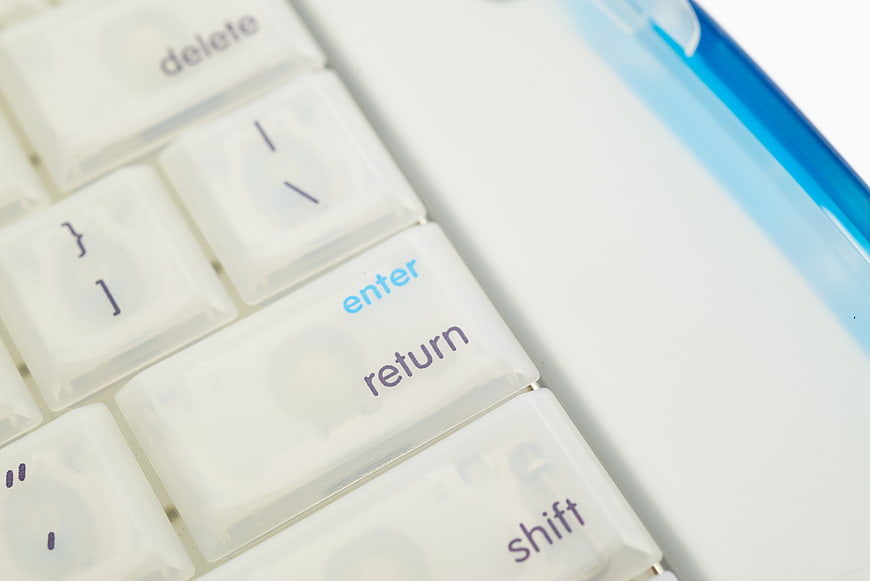 Close-up of white computer keyboard with blue enter key