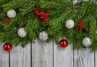 Christmas fir branches with red and silver baubles on white wood