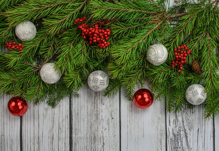 Christmas fir branches with red and silver baubles on white wood