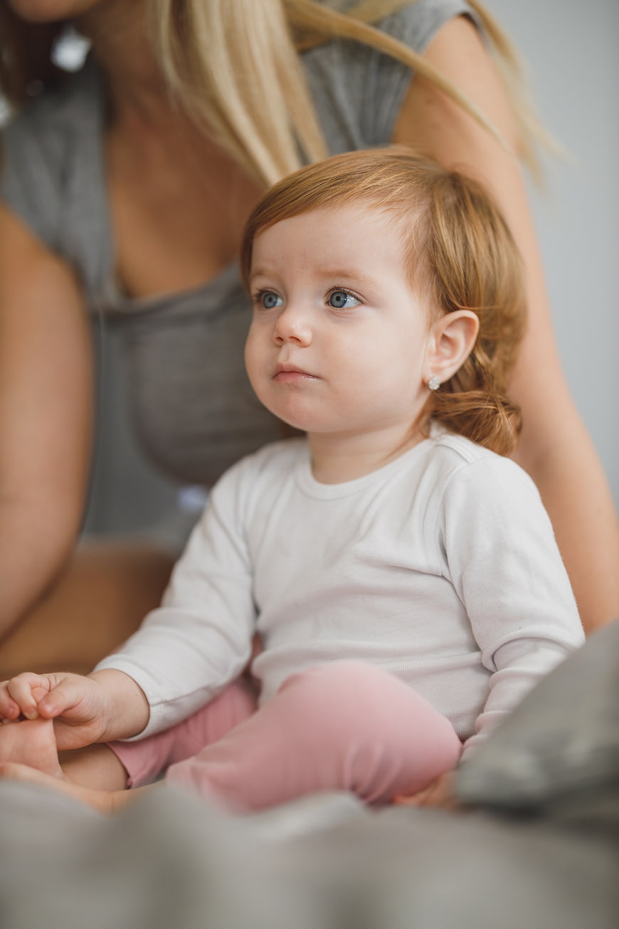 Cute Toddler Girl with Blue Eyes Sitting on Bed