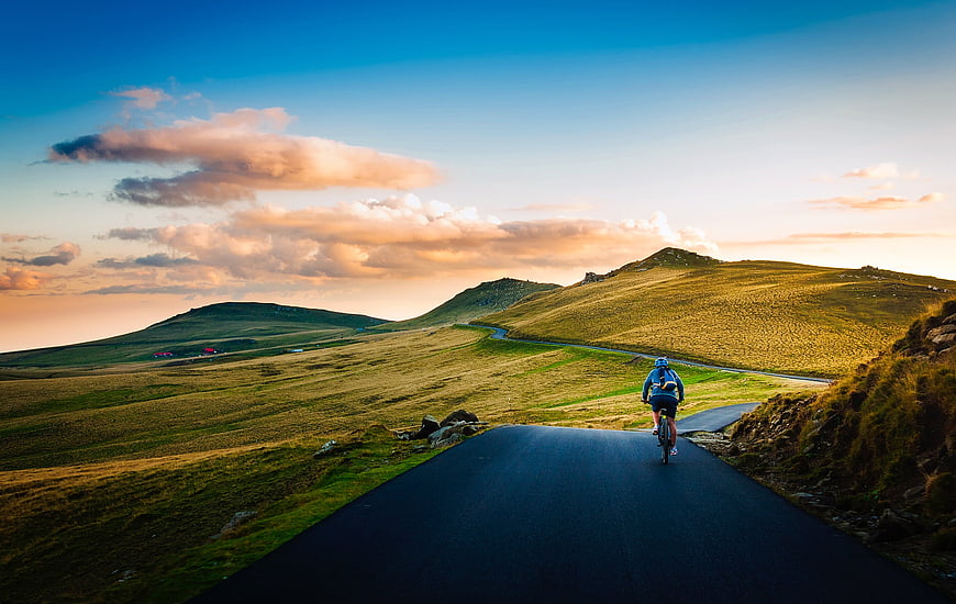Cyclist Riding on Winding Mountain Road at Sunset