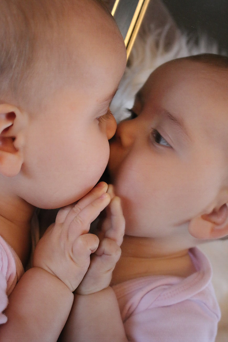 Baby Kissing Own Reflection In Mirror Close Up