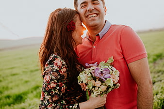 Happy couple laughing in field with bouquet