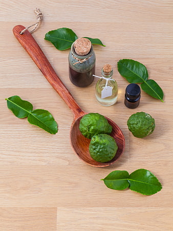 Kaffir lime leaves and essential oil on wooden spoon