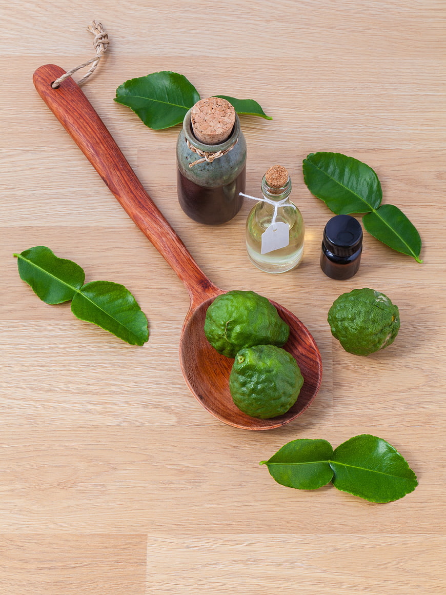 Kaffir lime leaves and essential oil on wooden spoon
