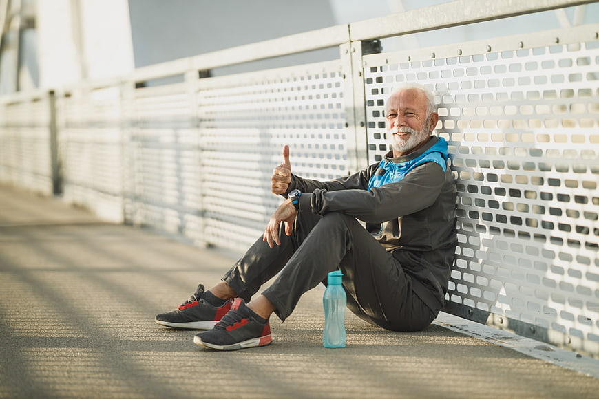 Happy Senior Man Resting After Outdoor Run on Bridge