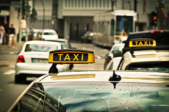 Yellow Taxi Sign on Car Roof in City Traffic
