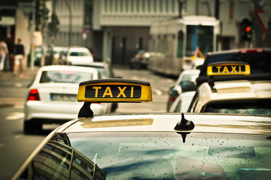 Yellow Taxi Sign on Car Roof in City Traffic