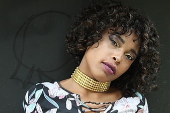 Portrait of stylish woman with curly hair and gold necklace