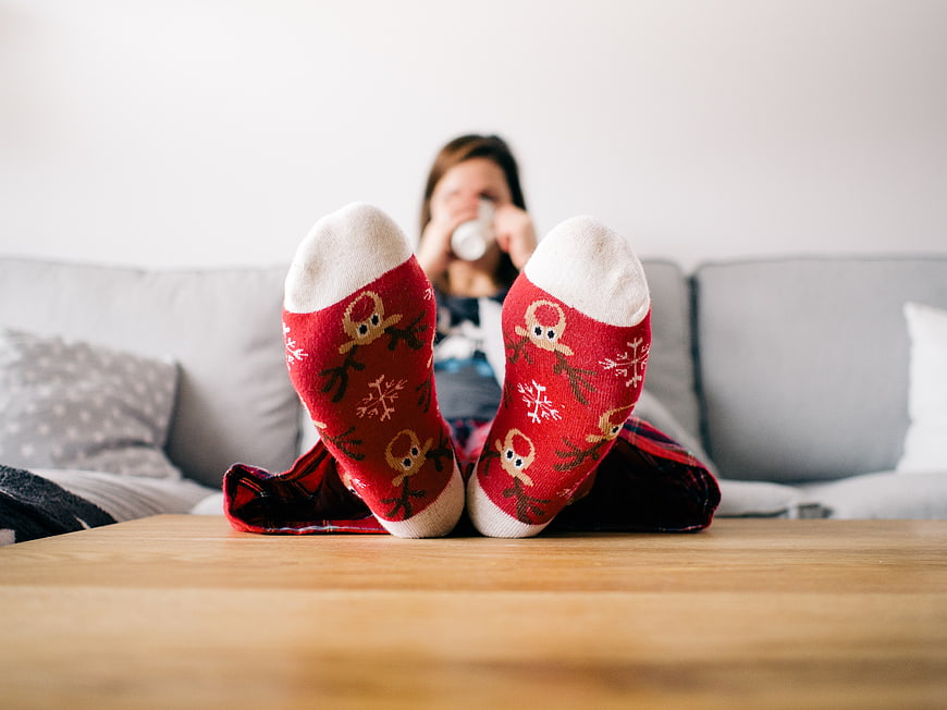 Woman relaxing on sofa wearing red reindeer Christmas socks
