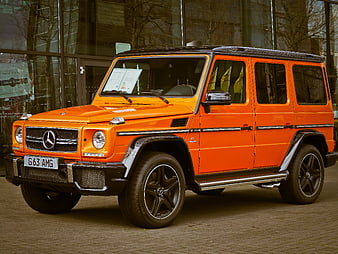 Orange Mercedes-Benz G63 AMG SUV Parked Before Glass Facade