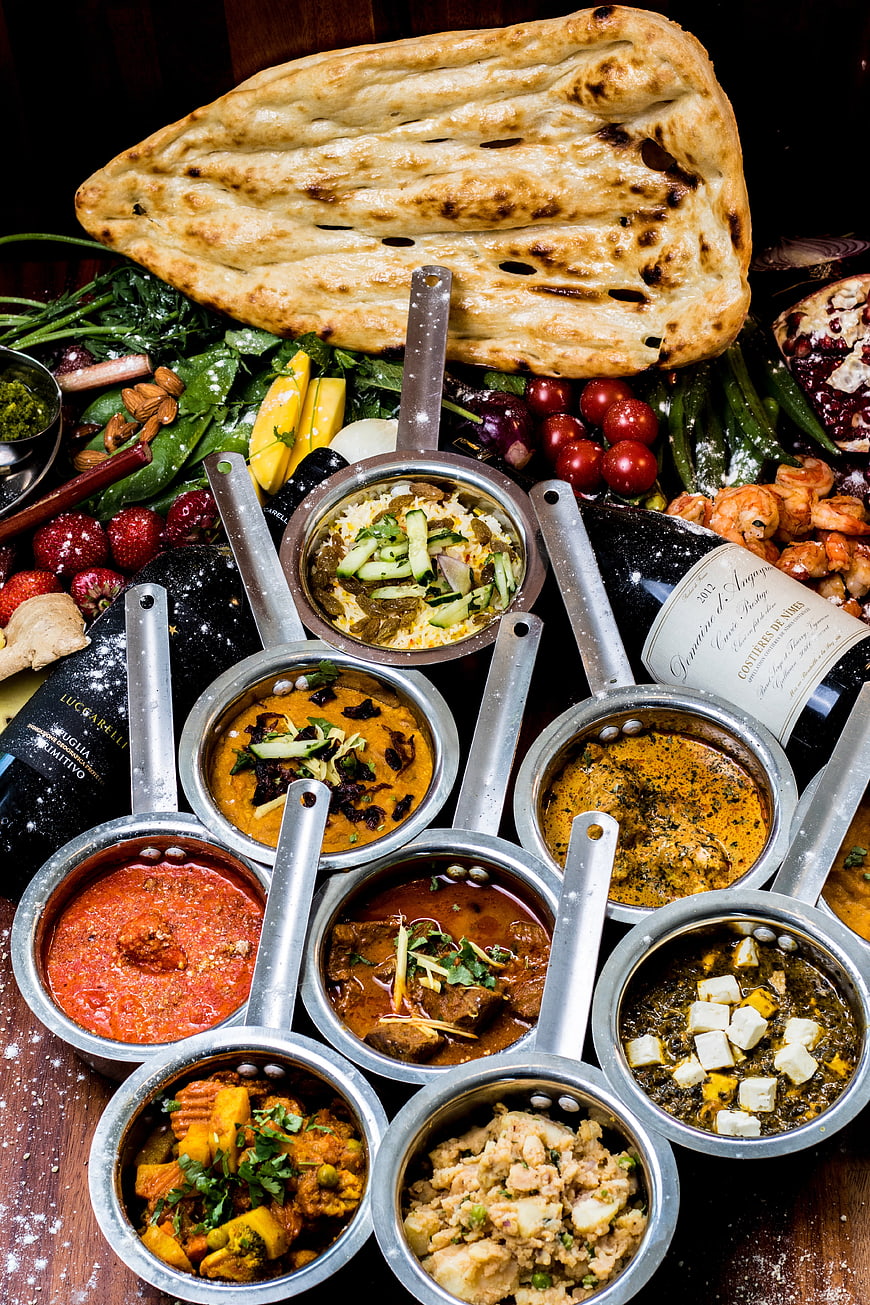 Overhead view of assorted Indian curries and naan bread spread