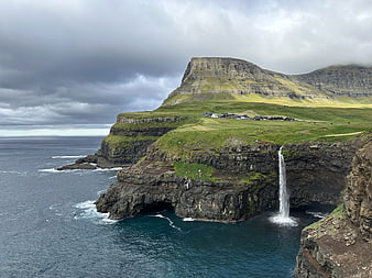 Dramatic coastal landscape with waterfall and village on cliffs