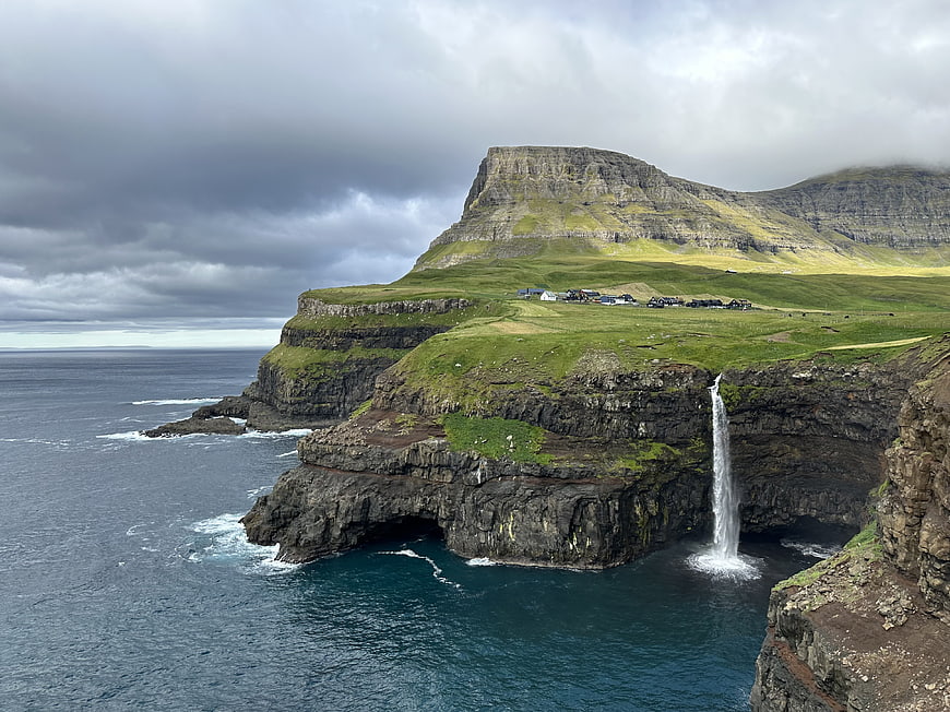 Dramatic coastal landscape with waterfall and village on cliffs