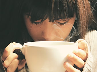 Close-up of woman holding steaming coffee cup with melancholic mood
