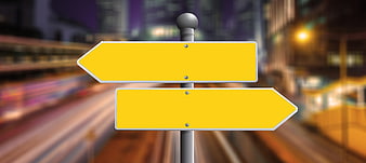 Yellow directional signpost with blurred city background