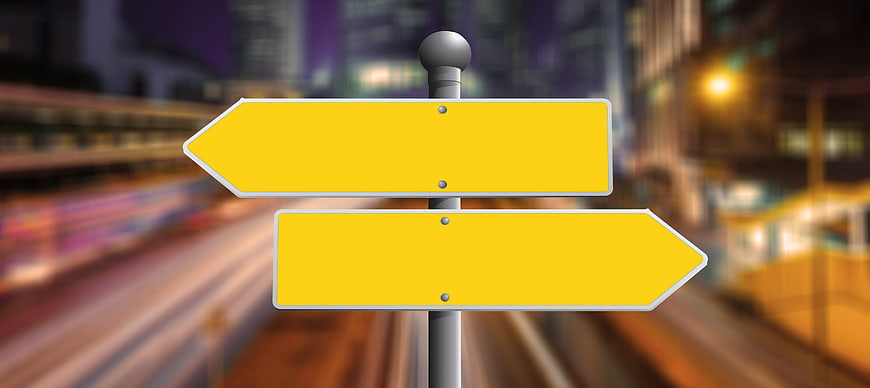 Yellow directional signpost with blurred city background