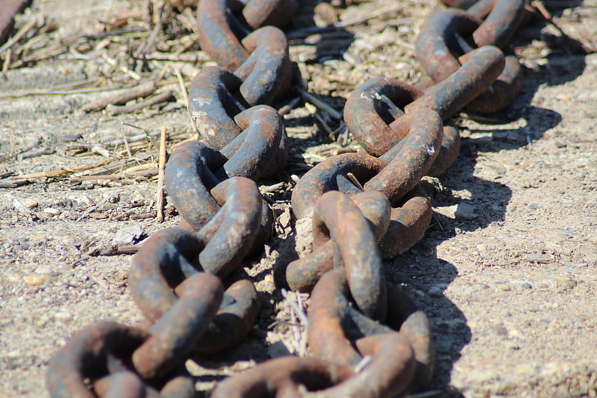 Rusty metal chains lying on sandy ground