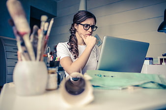Thoughtful female artist working on laptop in creative studio