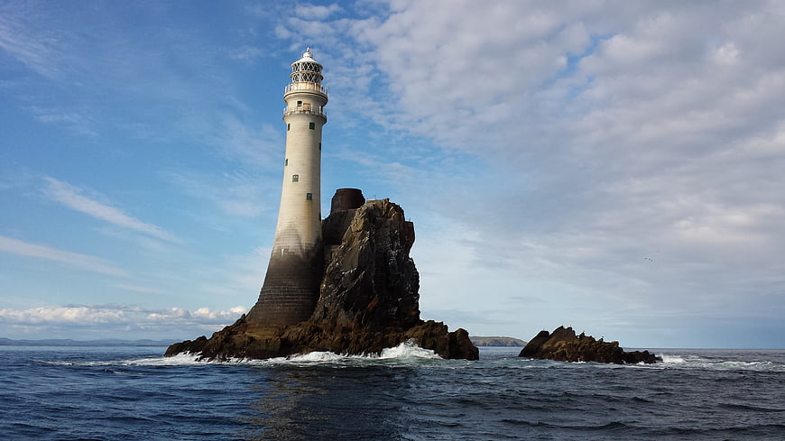White Lighthouse on Rocky Island in Blue Ocean