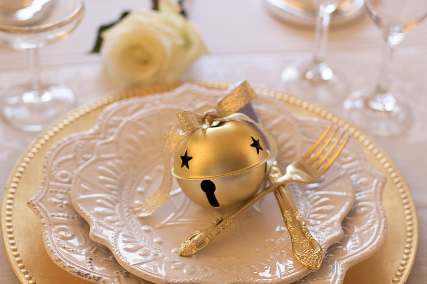 Elegant Christmas Table Setting With Gold Bell Ornament And White Plates