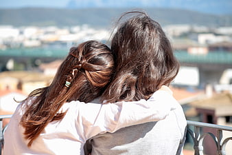 Two women hugging on balcony overlooking city