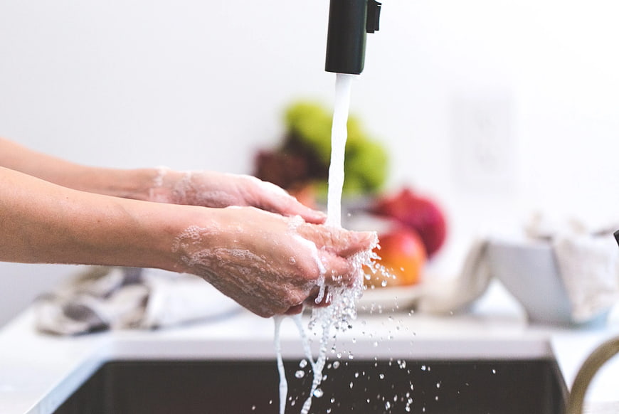 Close-up of hands washing with soap under running water