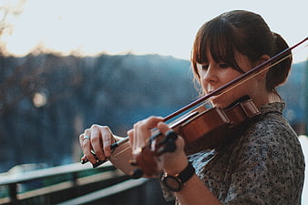 Young woman playing violin outdoors with blurred background