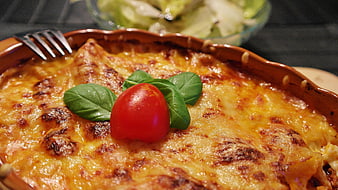 Close-up of baked lasagna with tomato and basil garnish
